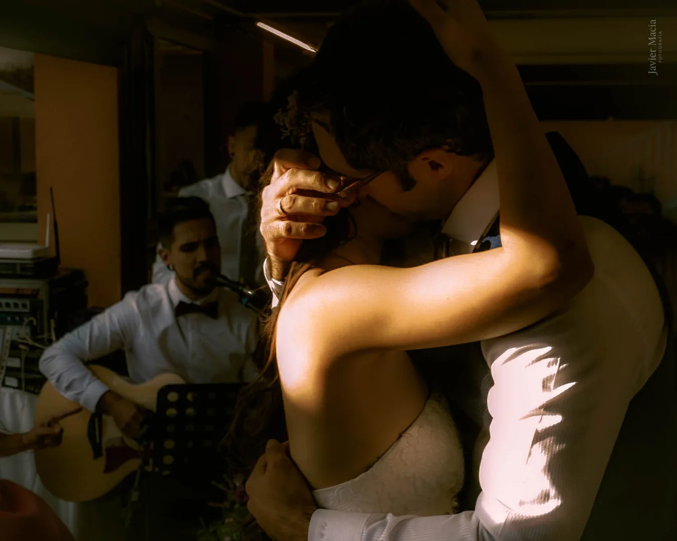 Pareja recién casados abrazados entre sombras, iluminados con la alianza